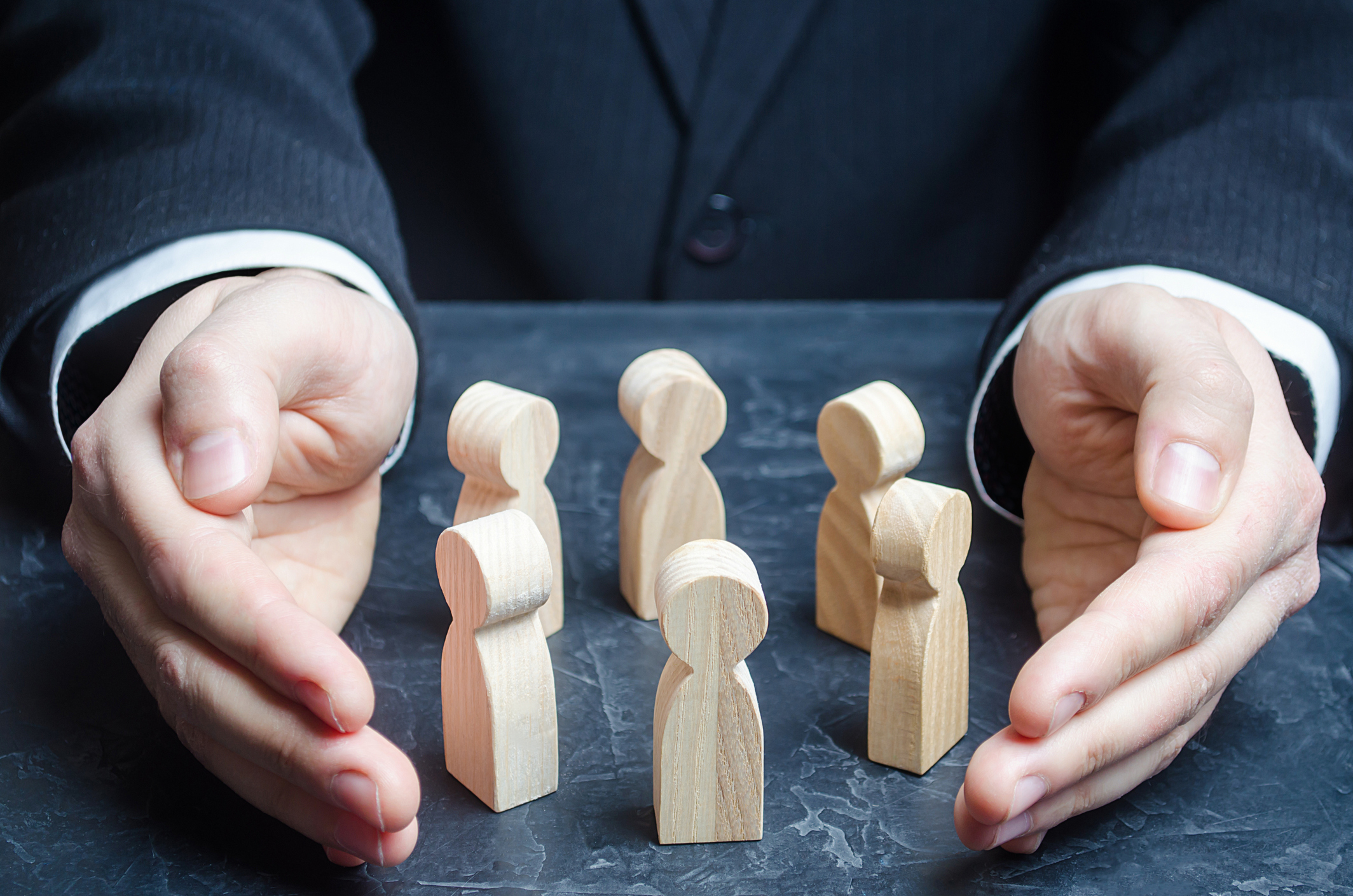 Businessman guards a circle of people with his hands. 