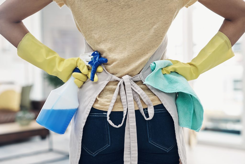 Shot of an unrecognizable woman using rubber gloves and disinfectant to clean her home