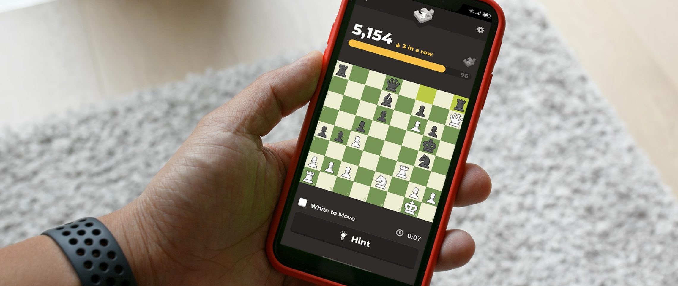 Closeup of a hand holding a cell phone with Chess.com app open.