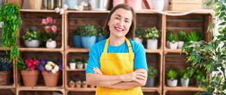 Proud woman standing in front of gardening business shelves.