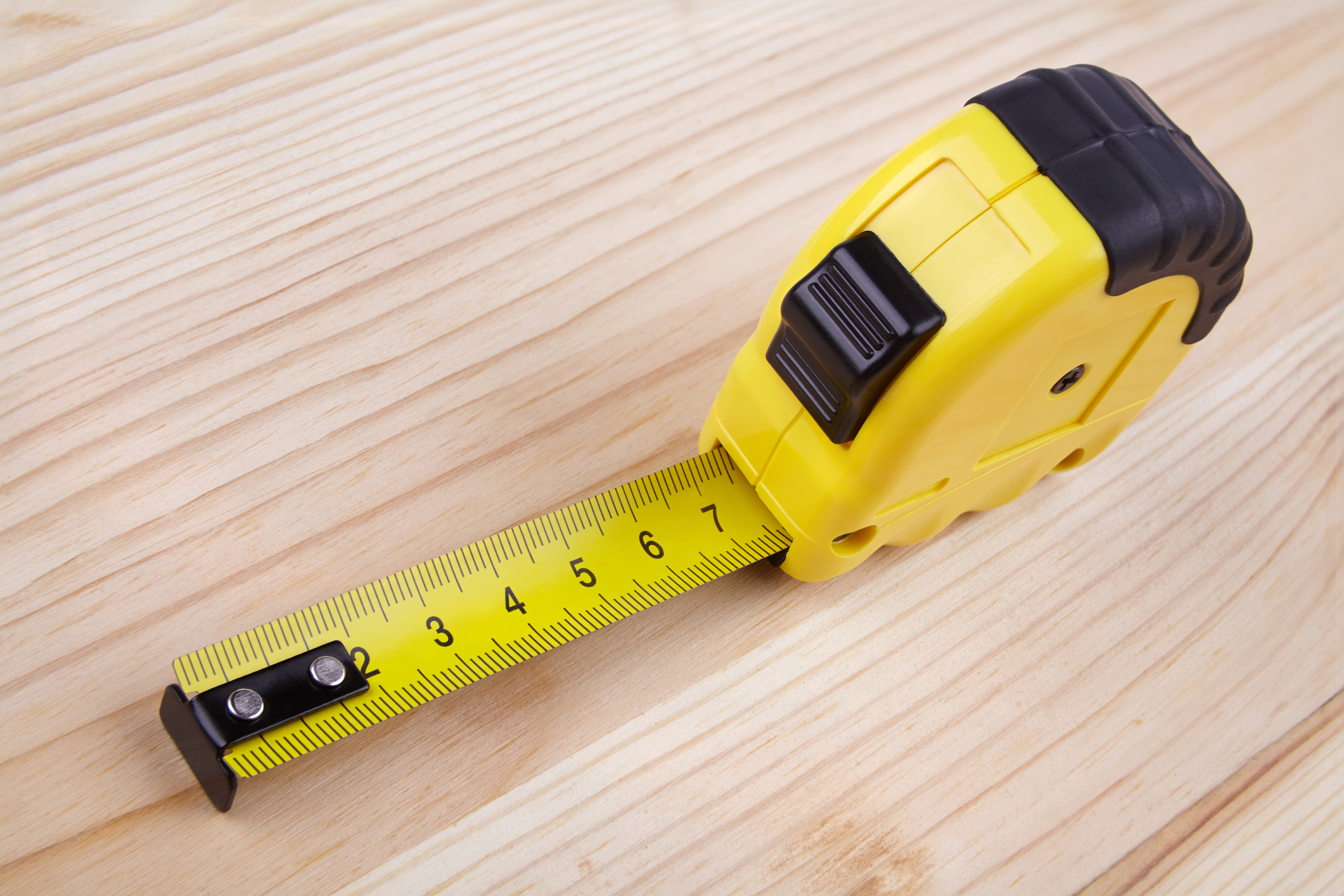 Yellow measuring tape on a wooden background