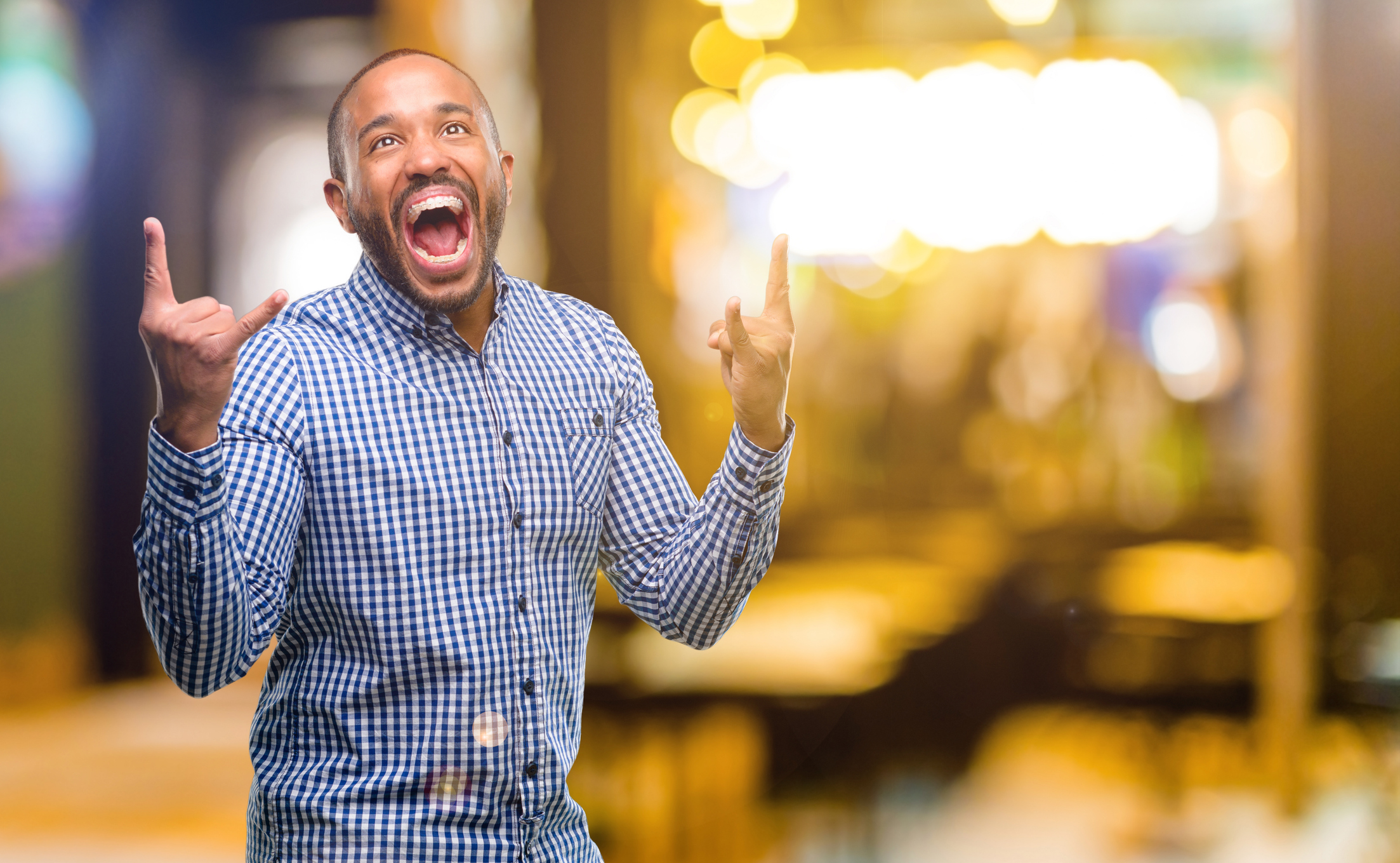 African american man with beard making rock symbol with hands, shouting and celebrating at night