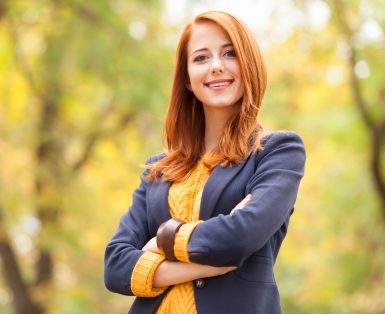 Redhead girl standing in nature with autumn leaves behind her