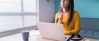 Thoughtful Latin American woman working online at home using her laptop computer - stay at home concepts