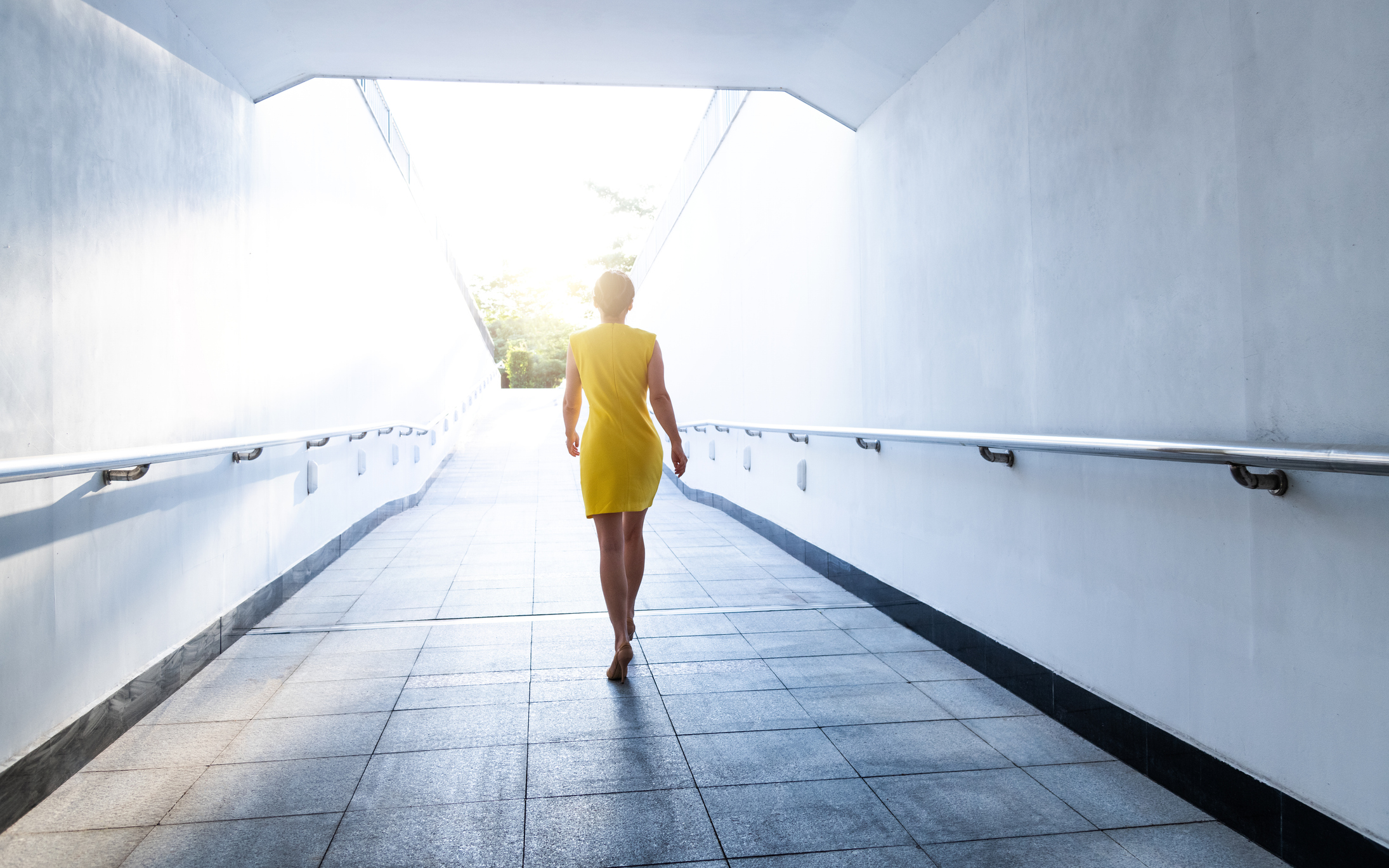 Young woman walking down a corridor towards lit exit
