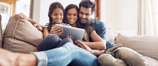 Shot of a mother and father using a digital tablet with their daughter on the sofa at home