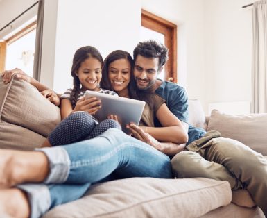 Shot of a mother and father using a digital tablet with their daughter on the sofa at home