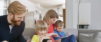 Family of four using mobile devices on couch