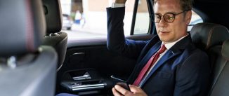 Businessman using smart phone sitting in car