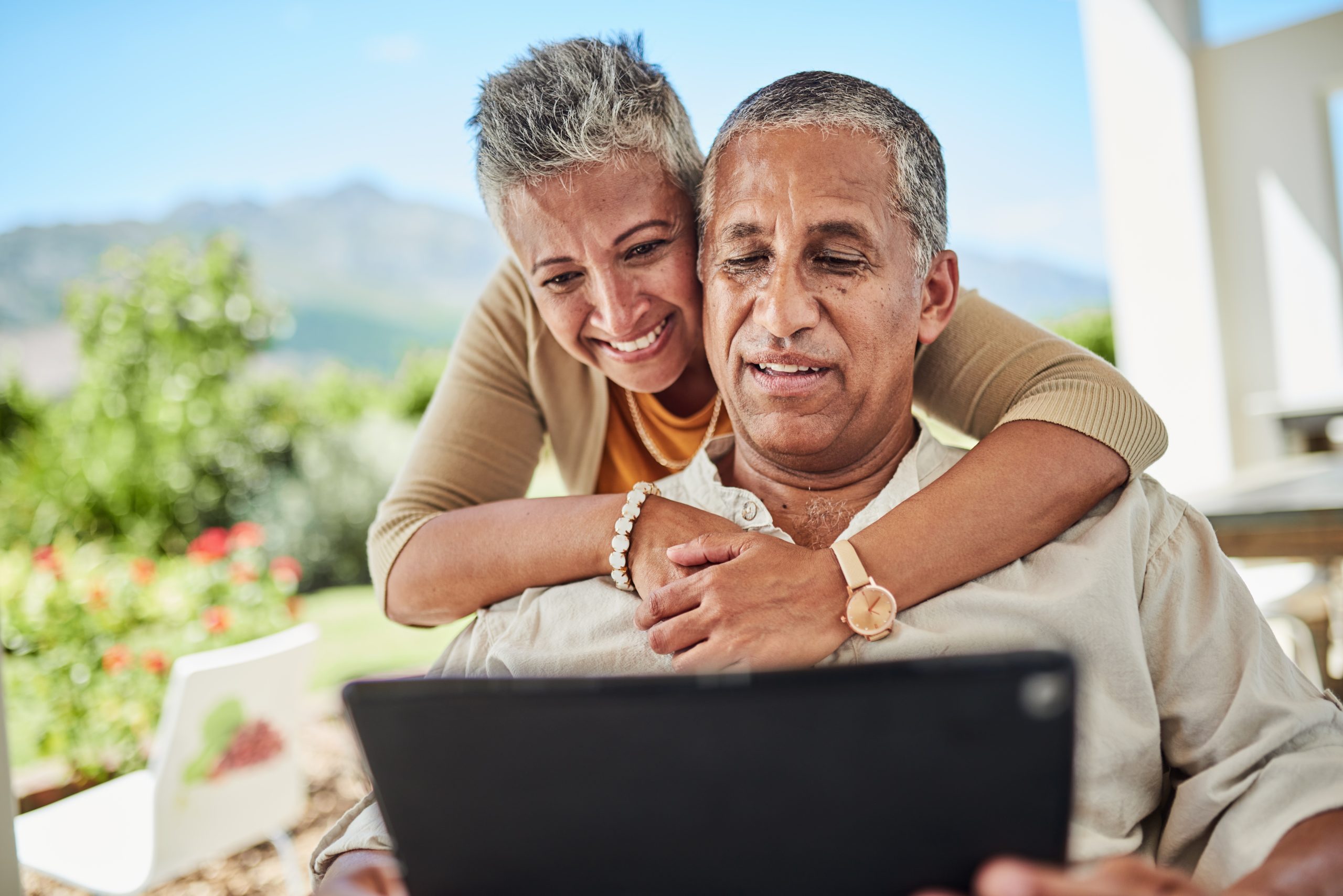 Family, digital tablet and video call with elderly couple hug, relax and bonding on a patio, happy, cheerful and loving. Couple, happy family and online conversation with senior man and woman outdoor