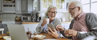 Close up of a senior couple using a phone and having breakfast