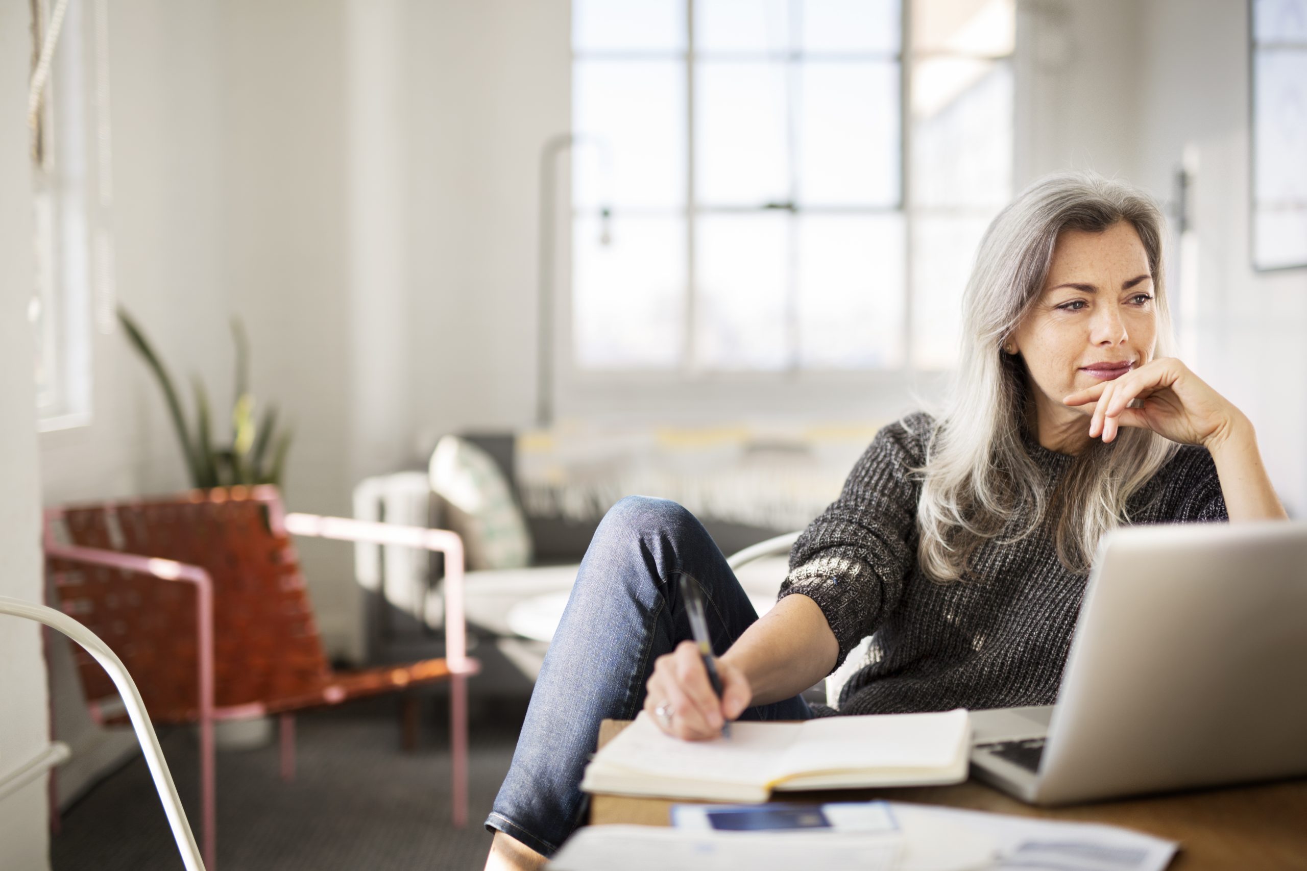 Mature woman writing in diary while working at home